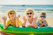 © galitskaya - Children sit on an inflatable mattress in sunglasses against the sea and have fun