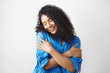 © shurkin_son - Self love concept. Isolated shot of beautiful pleased young dark skinned female with voluminous hairstyle embracing herself and closing eyes, enjoying soft fabric of her new stylish blue shirt