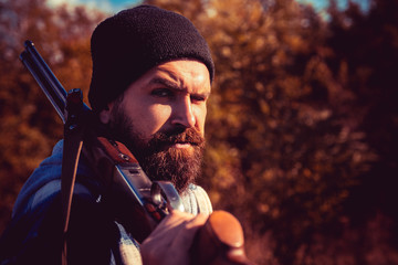 Wall Mural - Poacher in the Forest. Hunter with shotgun gun on hunt. Autunm hunting. Closed and open hunting season. Bearded hunter man holding gun and walking in forest.