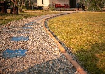 The path to the garden is made of small brown and white stone, Background of stone walk texture.