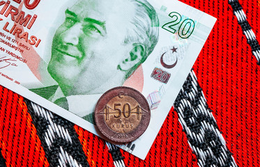 Turk money, metal coin and banknote. Turkish lira currency with Mustafa Kemal Ataturk portrait. Finance, banking and business in Turkey concept. Traditional ottoman red tablecloth background.