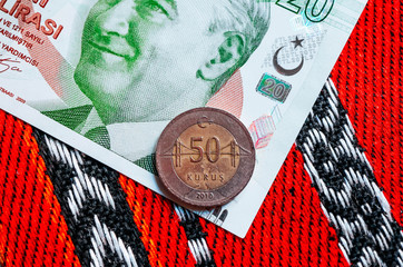 Turk money, metal coin and banknote. Turkish lira currency with Mustafa Kemal Ataturk portrait. Finance, banking and business in Turkey concept. Traditional ottoman red tablecloth background.