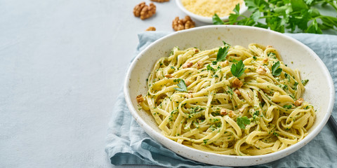 Poster - Banner with pesto pasta, bavette with walnuts, parsley, garlic, nuts, olive oil. Side view, long side, copy space, blue background.