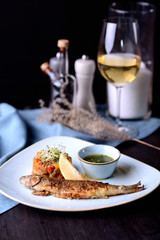 Wall Mural - grilled fish with vegetables and lemon on the background of a glass of white wine