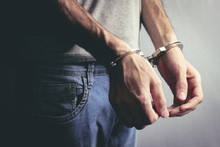 Young Man Hand Handcuffs On Dark Background