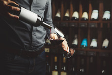 Close Up Shot Of Sommelier Pouring Red Wine From Bottle In Glass On Underground Cellar Background