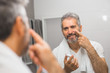 © cherryandbees - smiling middle aged bearded man applying face cream in bathroom