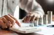 © Pichsakul - Businessman accountant Calculating on data documents And pile Stack Of coins, the savings money investment. financial Budget planning concept