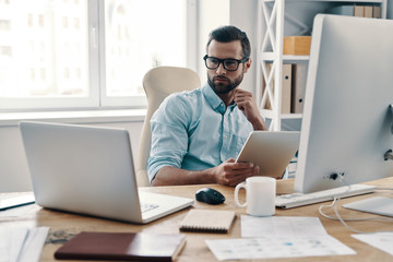 Wall Mural - Innovation. Young modern businessman working using digital tablet while sitting in the office