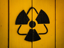 Radioactivity Sign, Close-up. Sign Of Radiation On A Yellow Wooden Board. Radioactive Sign - Symbol Of Radiation. Yellow And Black Radioactive Hazard, Ionizing Radiation, Nuclear Danger Warning Symbol
