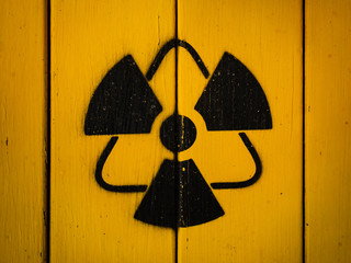 Radioactivity sign, close-up. Sign of radiation on a yellow wooden board. Radioactive sign - symbol of radiation. Yellow and black radioactive hazard, ionizing radiation, nuclear danger warning symbol