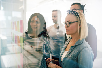 Wall Mural - Work colleagues brainstorming with sticky notes on an office wal