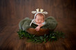 © Oksana - Newborn baby boy in a hat a bamby sleeps in an antique brown wooden bowl