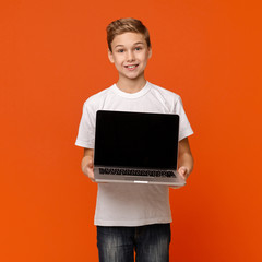 Happy smiling boy showing blank laptop computer