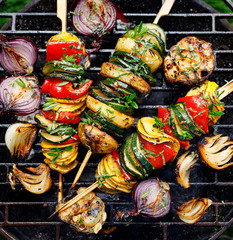 Vegetarian skewers, grilled vegetable skewers of zucchini, peppers and potatoes with the addition of aromatic herbs and olive oil on the grill outdoors. Grilled food