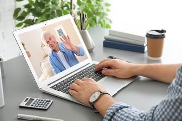 Poster - Man using laptop for conversation via video chat at table, closeup