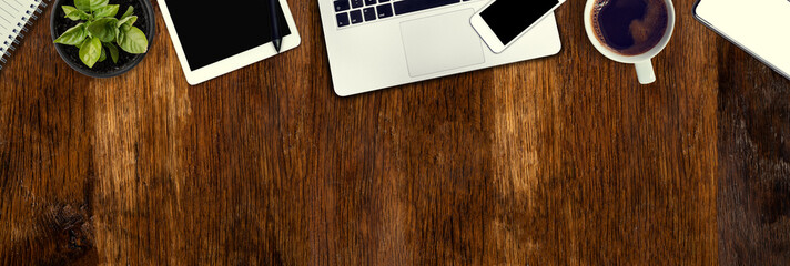 Old oak desk from above. Computer, telephone and tablet necessary tools at work. Office work in vintage style. Wide banner with copy space.