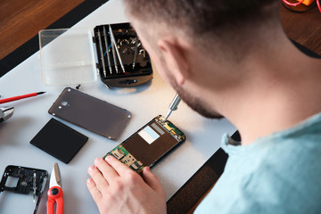 Wall Mural - Technician repairing mobile phone at table, closeup