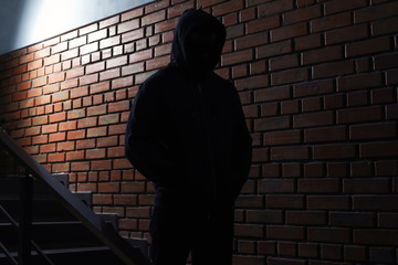 Wall Mural - Silhouette of mysterious man in hoodie indoors. Dangerous criminal