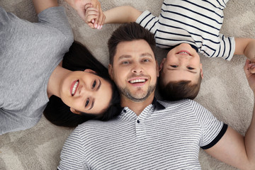 Poster - Happy parents and their son lying together on floor, view from above. Family time