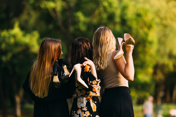 Canvas Print - girls hold their shoes in their hands. back view. park