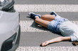 Teenage schoolkid lying on the street after terrible car crash on pedestrian crossing