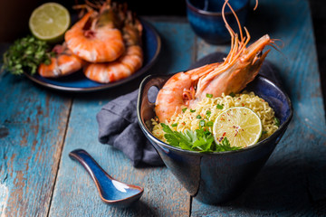 Wall Mural - A bowl of instant Chinese noodles with green onions, red hot chilli peppers, and shrimps on a dark rustic background