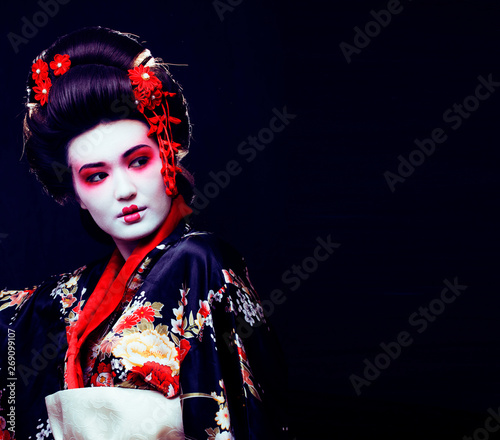 Fotografía young pretty real geisha in kimono with sakura and decoration on black backgroun