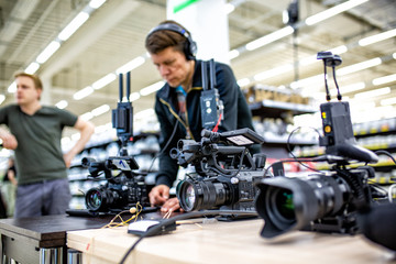 Videographer shooting a film or a television program in a studio with a professional camera, backstage