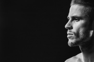 Muscular model young man with beard on dark background. Fashion portrait of brutal sexy strong muscle guy with modern trendy hairstyle. Model, fashion concept. Black and white.