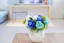 Blue Artificial Roses Bouquet In Ceramic Vase On Table In Living Room