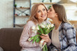 © Pixel-Shot - Happy daughter greeting her mother with bouquet of flowers at home