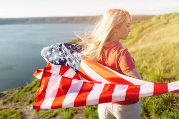 Wall Mural - Patriotic holiday. Young woman holding USA flag.