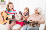 Joyful granddaughters with grandmother listening the guitar play