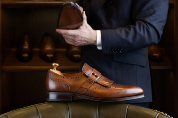 Brown full grain leather shoe in front of wooden display in men shoes boutique store.