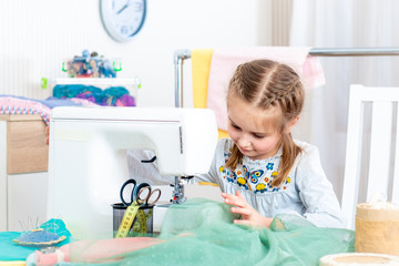 Little girl using sewing machine to make crafts in the workshop