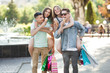 © olenachukhil - Group of young attractive people making shopping. Friends outdoors holding a shopping bags and smiling. Cheerful friends together.
