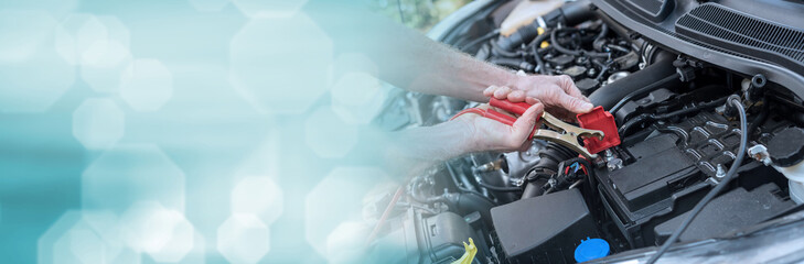 Wall Mural - Hands of car mechanic using car battery jumper cable. panoramic banner