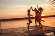 © BalanceFormCreative - Group of friends dancing and having fun on the pier by the lake on sunset.