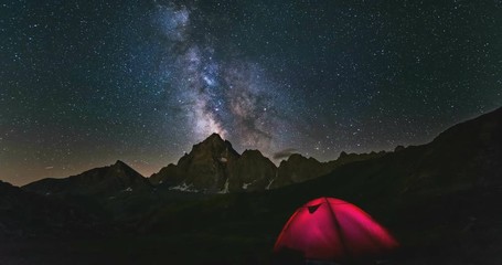 Wall Mural - time lapse milky way galaxy stars rotating over the alps, camping illuminated tent, snowcapped mount