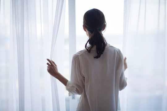 窓の外を見つめる女性の後ろ姿