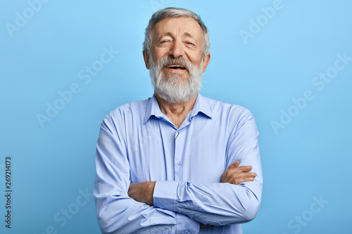 Fotografía friendly handsome man standing with crossed arms, laughing at something, looking at the camera
