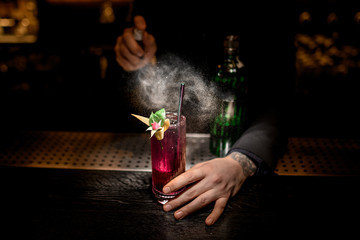 Bartender makes cocktail decorated with flower using sprayer