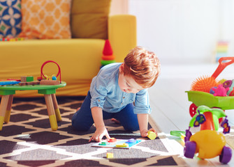 Wall Mural - cute toddler baby boy playing with toys on the carpet at home