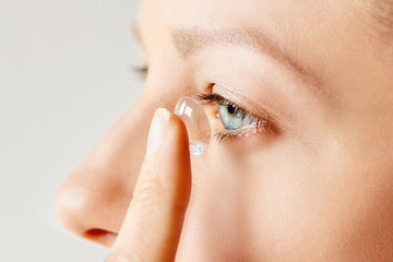 Wall Mural - Young woman puts contact lens in her eye. Eyewear, eyesight and vision, eye care and health, ophthalmology and optometry concept, selective focus