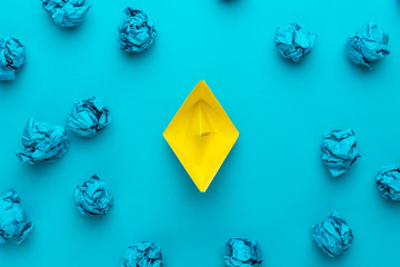 Wall Mural - new idea concept with crumpled office paper and yellow paper ship. top view of great business idea concept over blue background with yellow paper boat in the center