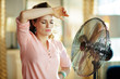 woman exhausted from summer heat while standing in front of fan