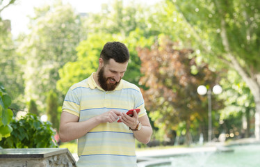 Handsome sporty bearded dark-haired man is using the phone.