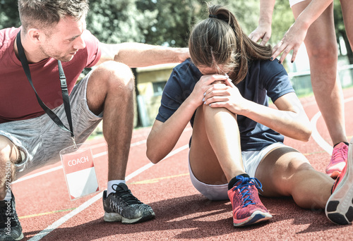 Fotomural Female athlete getting injured during athletic run training - Male coach taking