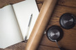 © Tomasz - Czysty otwarty notes z długopisem leży na drewnianej podłodze, obok leżą słuchawki muzyczne.